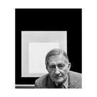 Black and white portrait of an older man in a suit with framed geometric artwork behind him.
